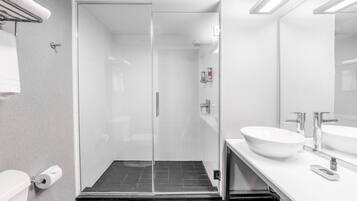 A modern bathroom with a glass-enclosed shower, a white sink, and a toilet.