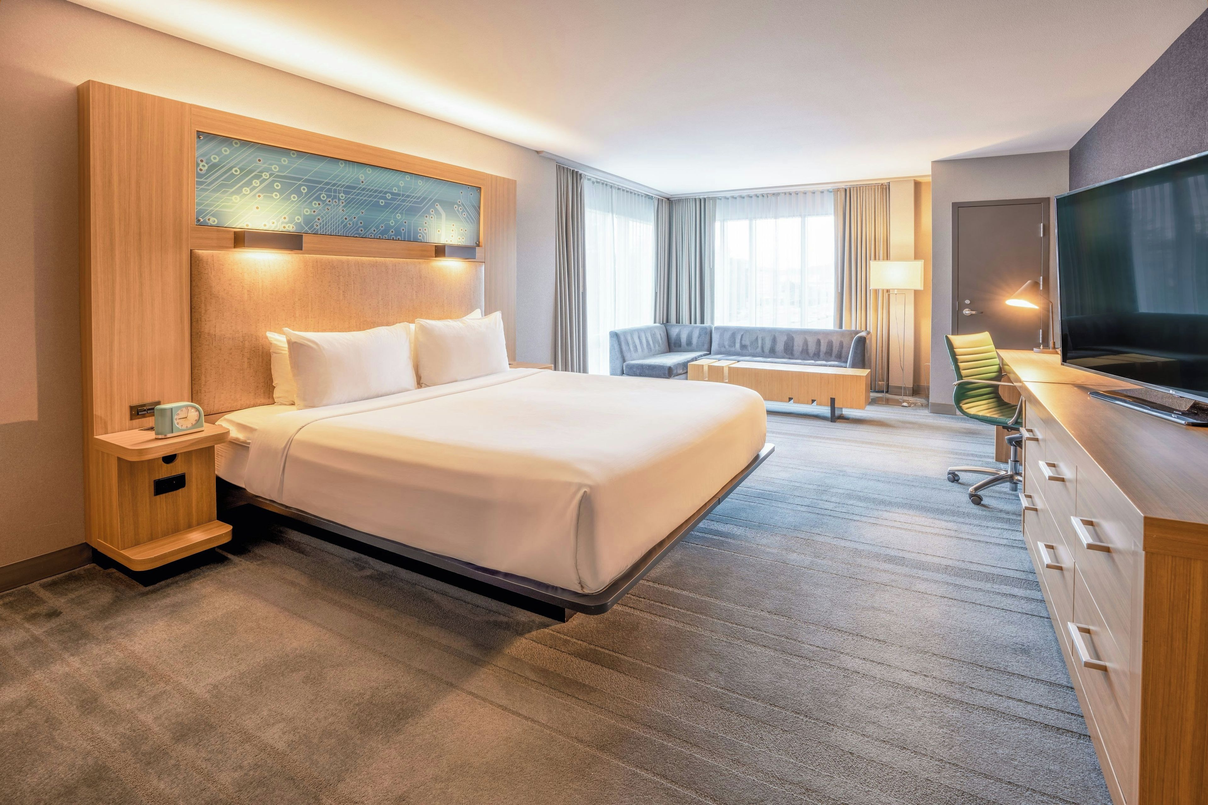 Quarto de hotel com uma cama grande, uma escrivaninha, televisão e área de estar.