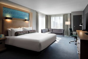 Une chambre d’hôtel moderne équipée d’un grand lit, d’un canapé, d’un bureau et d’une télévision.