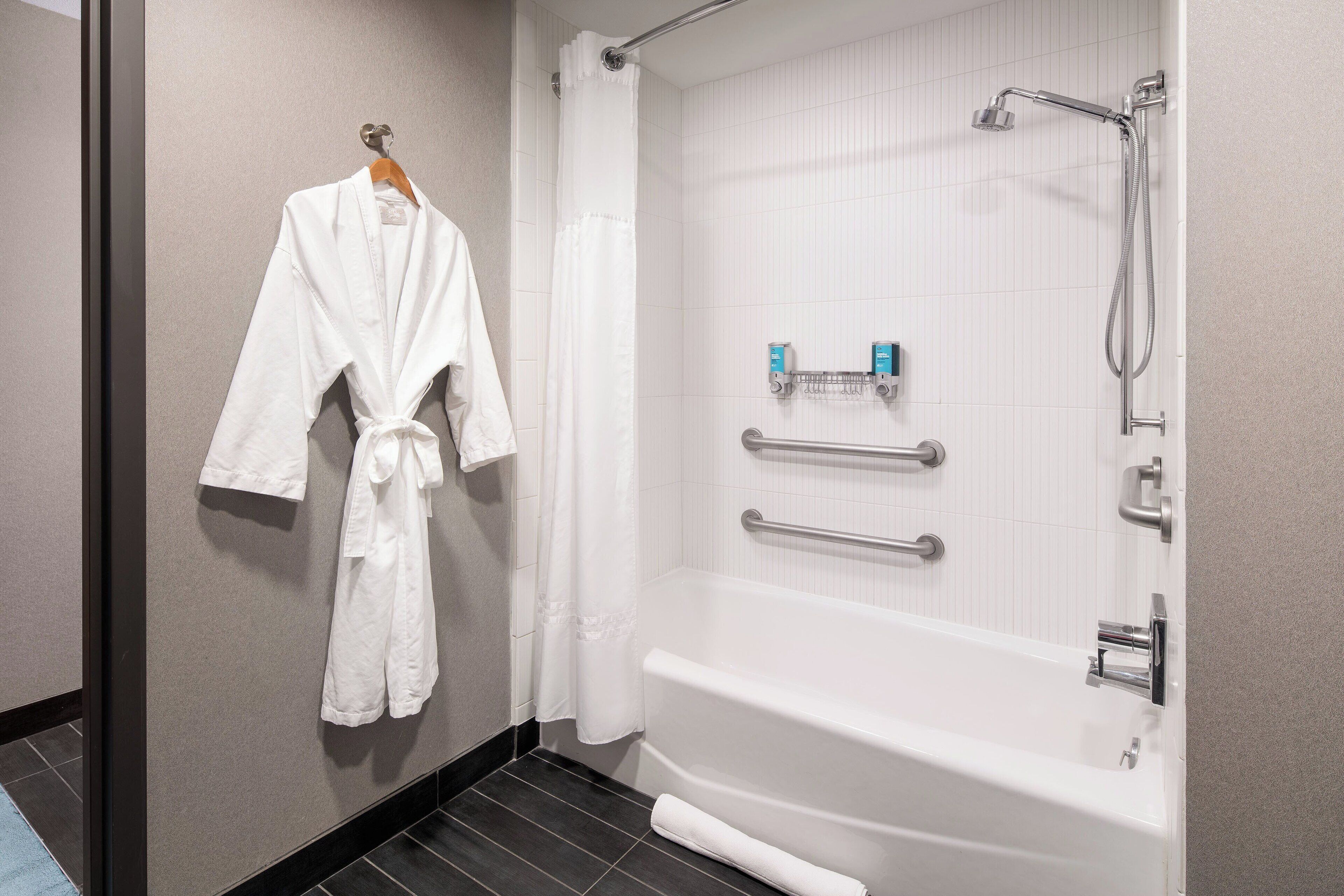 Une salle de bain équipée d’une baignoire, d’un porte-serviettes et d’une douche avec des barres d’appui.