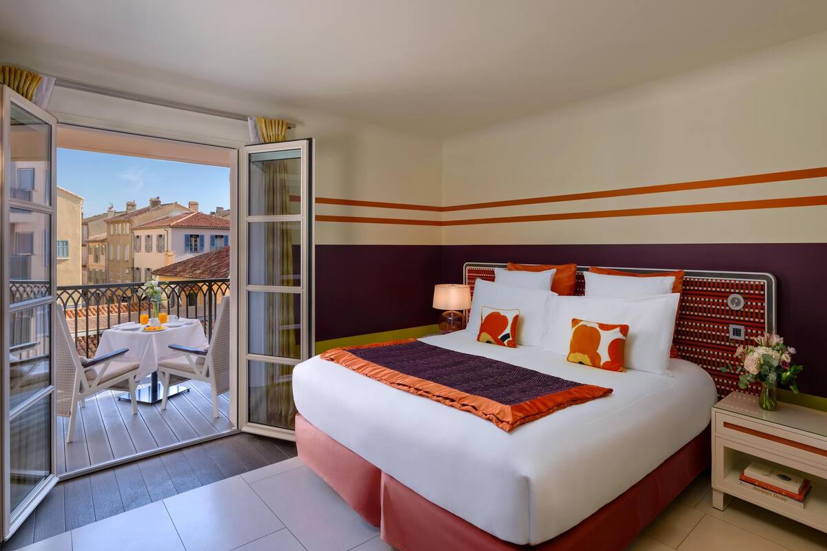 Une chambre d’hôtel comprenant un lit, une table de chevet, une table avec des chaises et un balcon avec une table et des chaises.