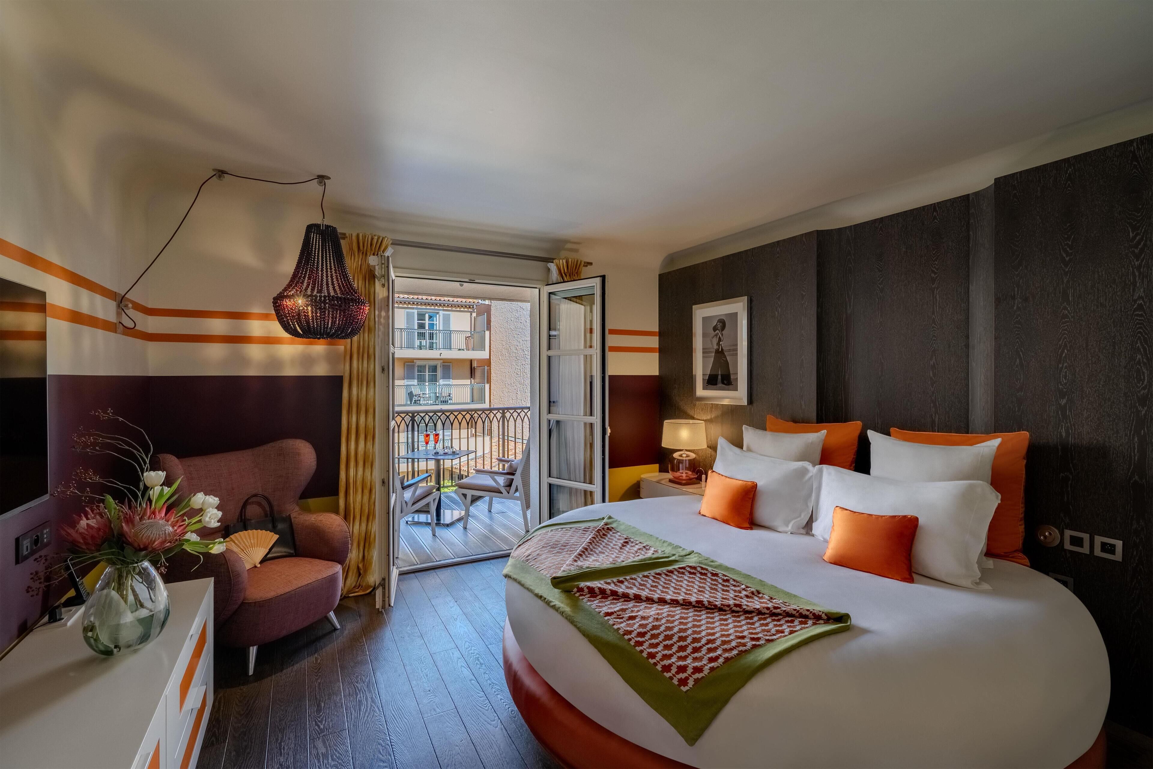 Une chambre d’hôtel avec un lit, une chaise, un bureau et un balcon donnant sur la vue.