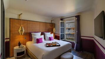 Une chambre d’hôtel avec un grand lit, des tables de chevet, une fenêtre avec des rideaux et une vue sur un bâtiment à l’extérieur.