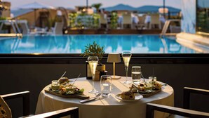 A dining table with a view of a pool and umbrellas in the background.
