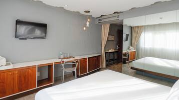 A hotel room with a bed, a desk with a chair, a television, and a bathroom with a shower.
