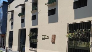 Un edificio con varios balcones, algunos con plantas, y un cartel que indica 'MAYO' y 'BLUE'.