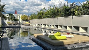Una piscina con una plataforma flotante, sillas de descanso y toallas.