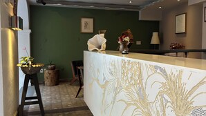 Zona de recepción con mostrador, pared verde y suelo estampado.