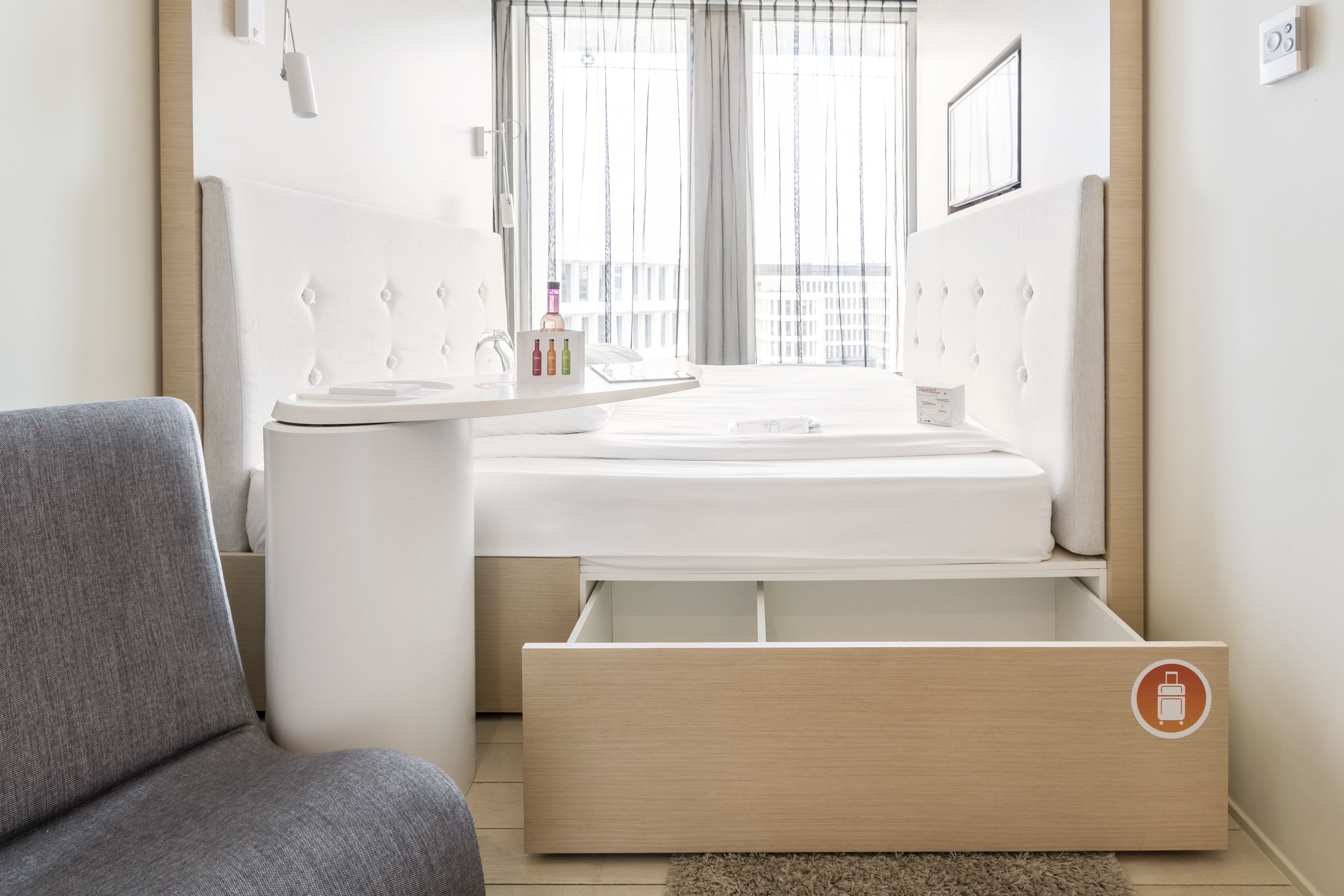 A modern bedroom with a bed, bedside table, and a built-in drawer unit.