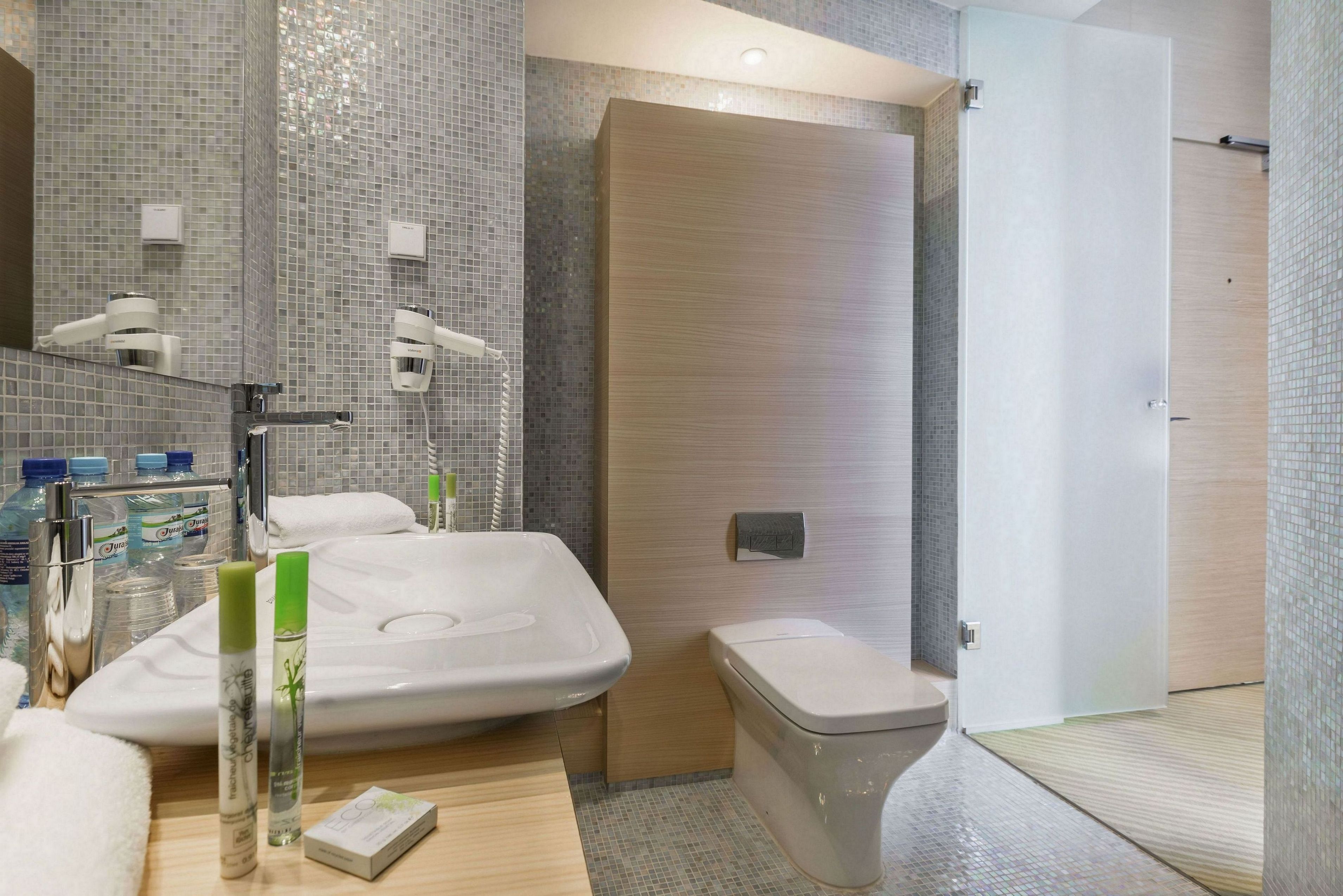 A modern bathroom with a large sink, toilet, and shower area.