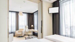 Una habitación de hotel moderna con cama, escritorio, silla y televisor.