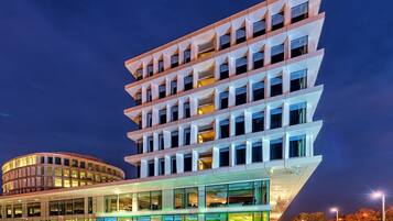 Un edificio moderno de varios pisos con un diseño angular distintivo, que cuenta con ventanas grandes y fachada de vidrio.