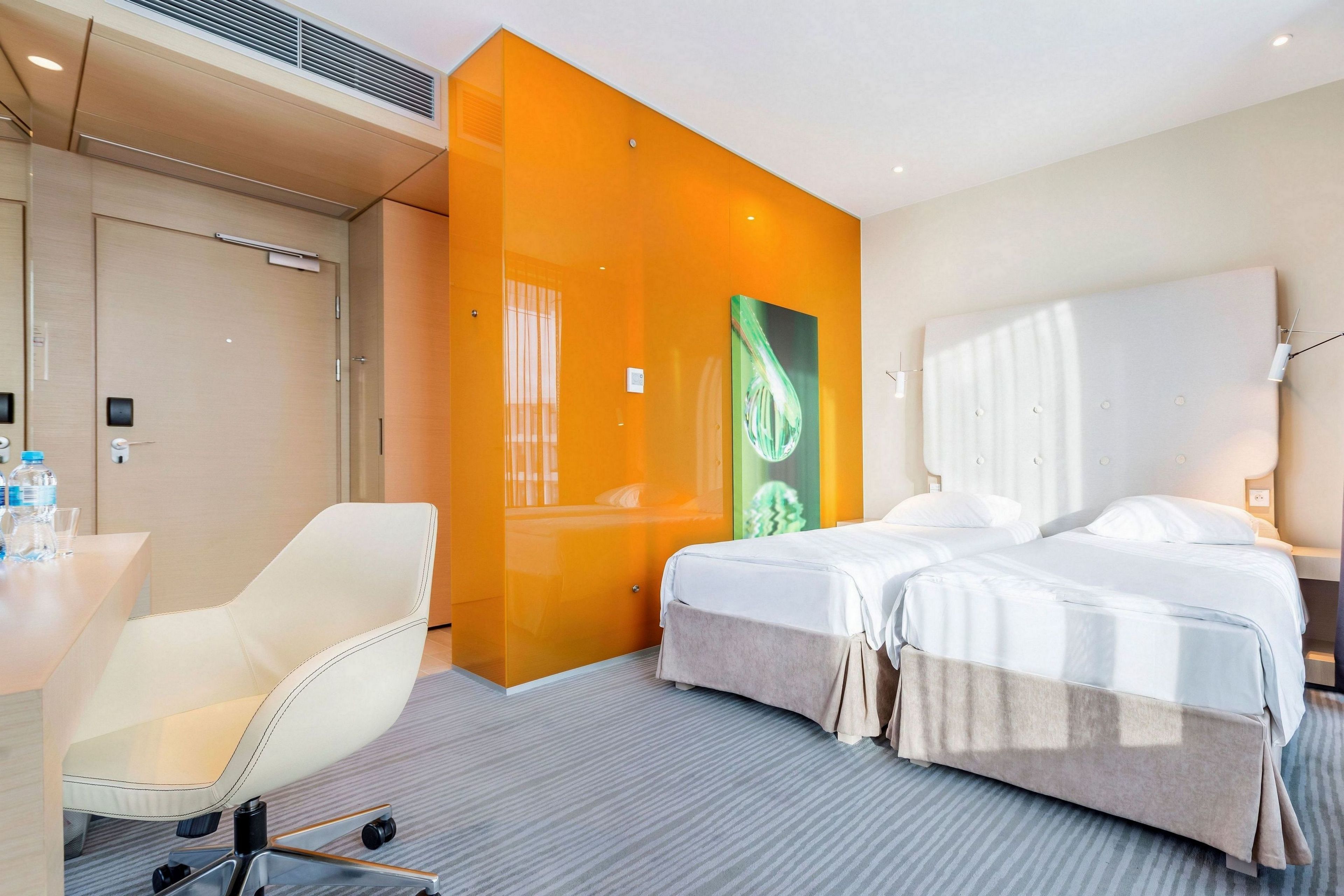 Une chambre d’hôtel avec un lit, une chaise, un bureau et une grande fenêtre.