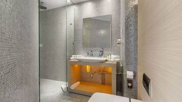 A modern bathroom with a glass-enclosed shower, a large mirror, and a sink with a towel rack.