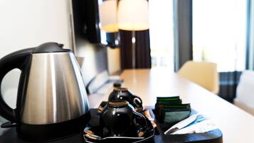 A kitchen area with a kettle, a coffee maker, and a stack of cards on a table.