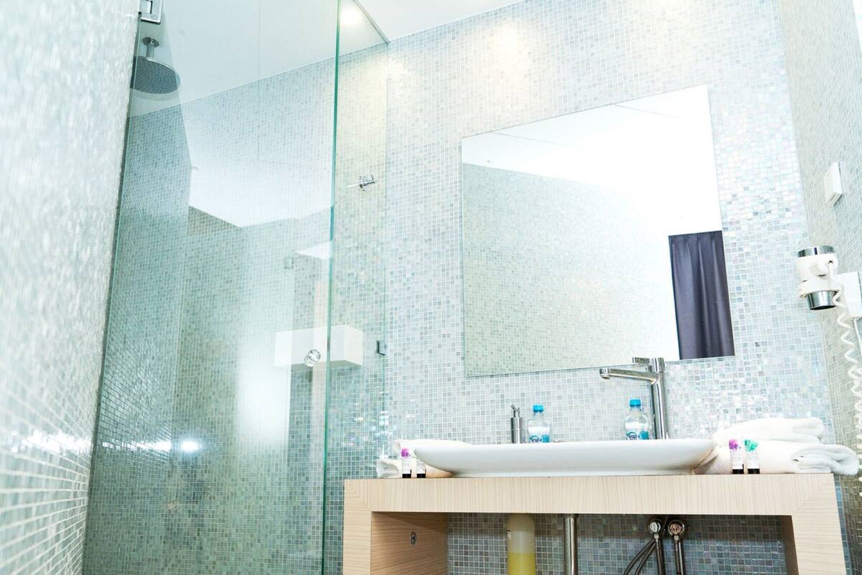 Un baño moderno con cabina de ducha de vidrio, lavabo con espejo y pared de azulejos.