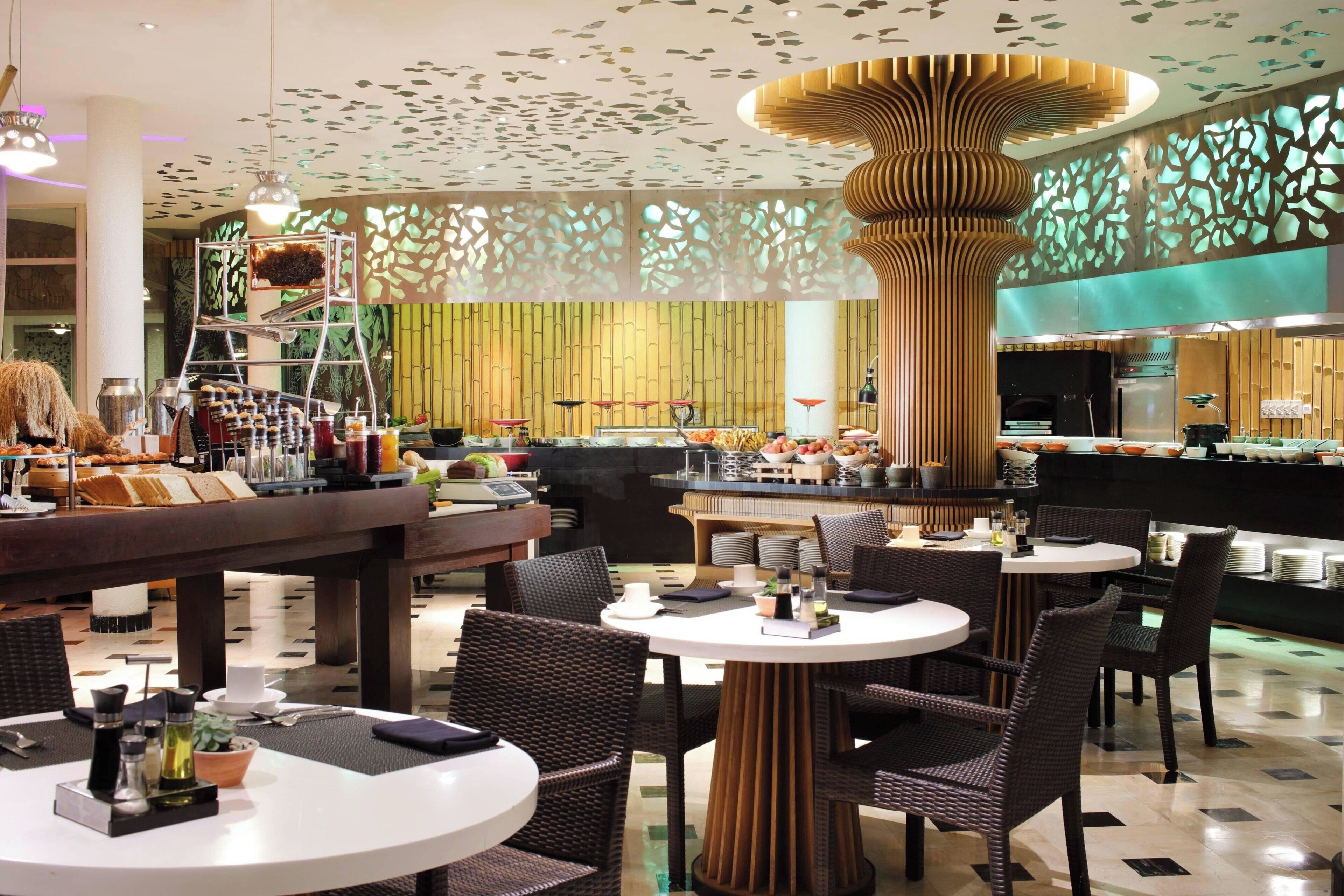 A modern restaurant with round tables, wicker chairs, and a central decorative column.