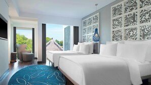 A modern hotel room with a large bed, a seating area with a chair and a small table, a patterned rug, and a view of the outside. - Le Meridien Bali Jimbaran (Jimbaran)