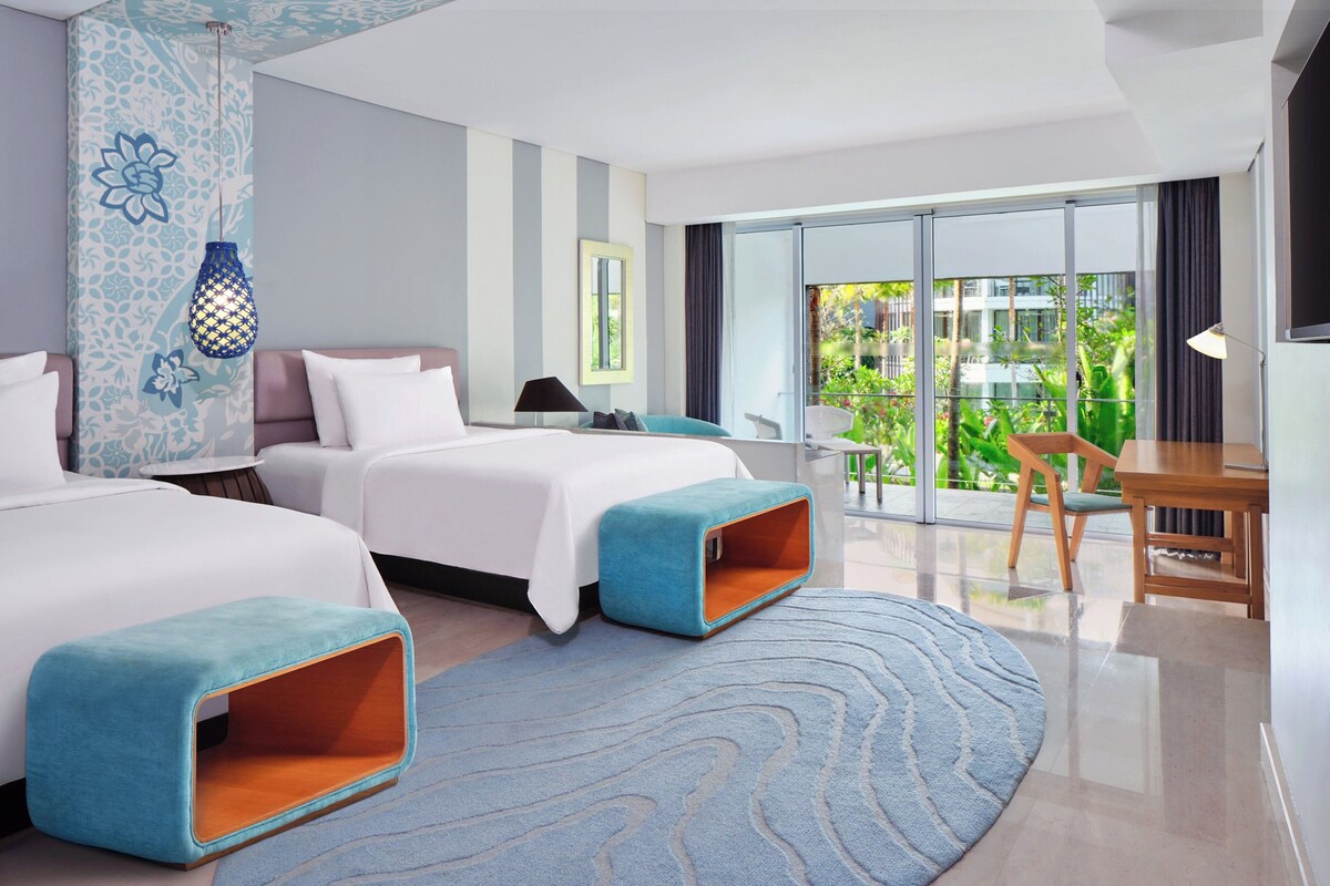 A modern hotel room with two beds, a balcony with a view, and a dining area.