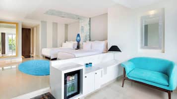 Una habitación de hotel moderna con cama, sofá, minibar y vistas al exterior.