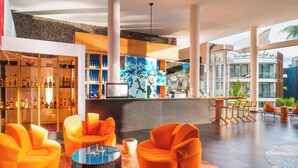 En moderne lobby med orange siddepladser, et barområde og udsigt til bygningens facade.