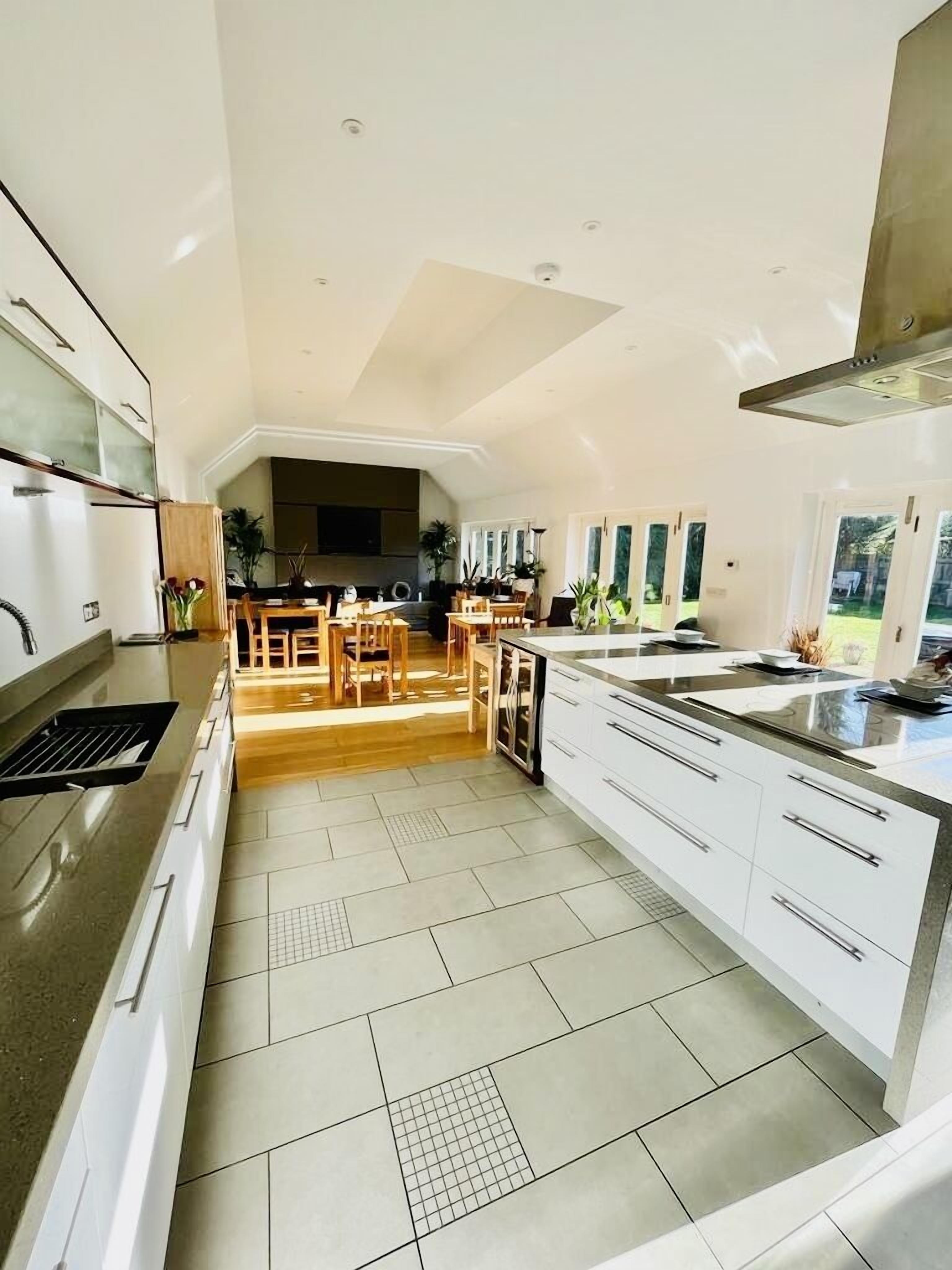 Una cocina moderna con una isla central, muebles blancos y una zona de comedor con mobiliario de madera.