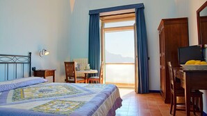A bedroom with a bed, a desk, and a chair. There is a window with curtains and a view of the outside. - Villa Rina (Amalfi)