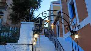 Una escalera con barandillas de metal ornamentadas y luces en la pared que conduce a la entrada de un edificio.