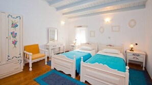 Un dormitorio con dos camas, una silla, un tocador y un espejo.