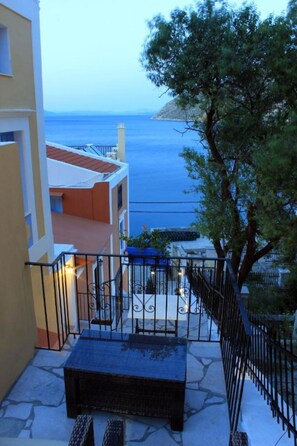 A balcony with a view of the sea, a bench, and a railing. - Dorian Hotel (Symi)