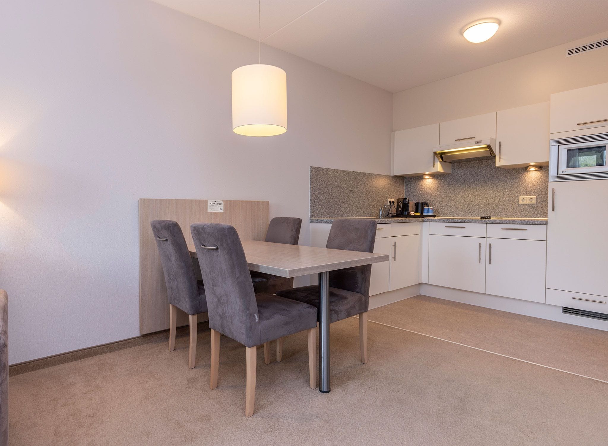 A modern kitchen with white cabinets, a granite countertop, and a built-in oven.