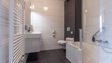 Une salle de bain moderne équipée de toilettes, d’un lavabo et d’une douche.