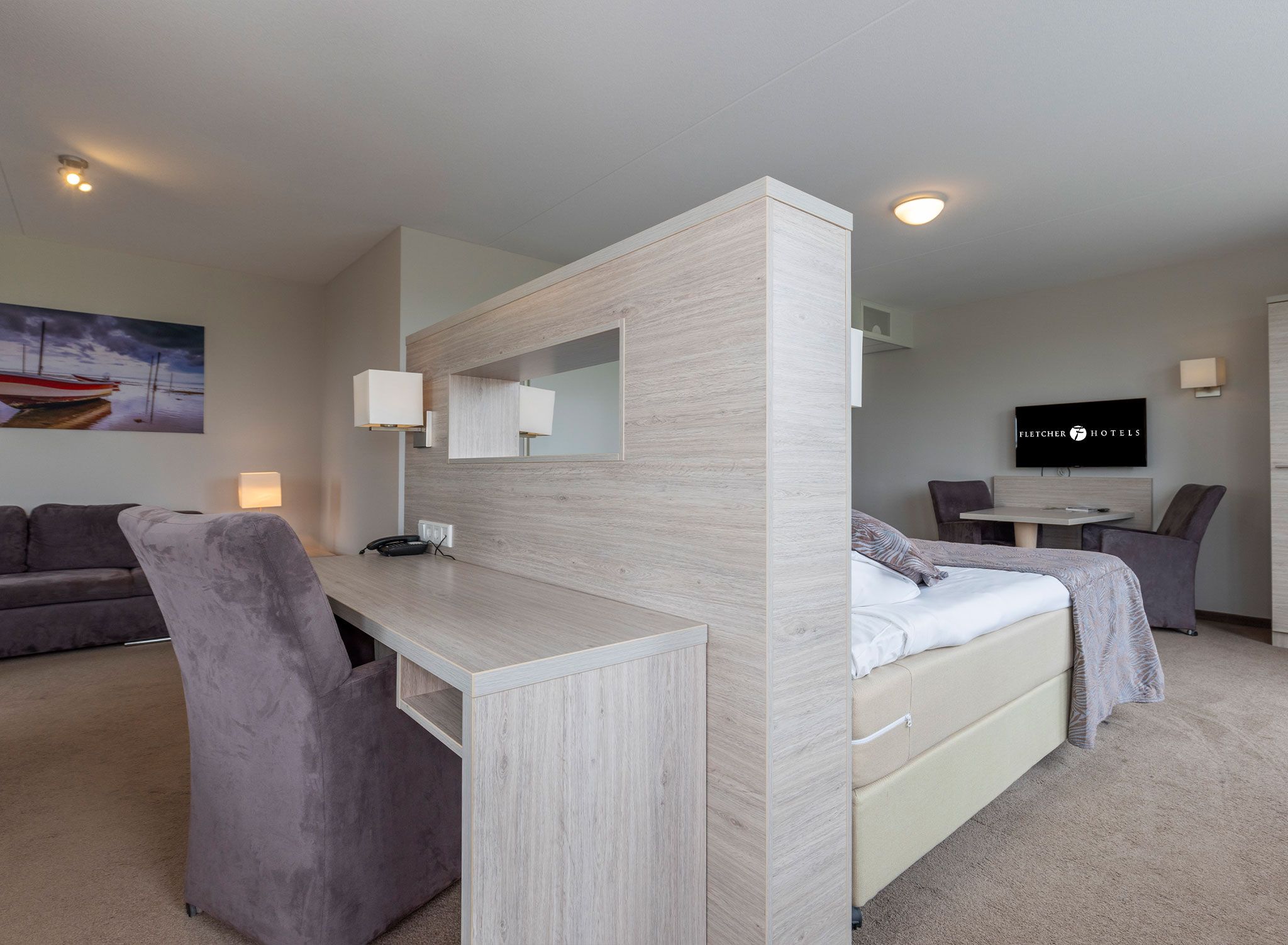 Quarto de hotel moderno com escrivaninha, duas camas, um sofá e uma TV.