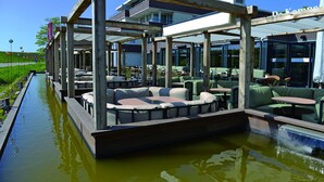 An outdoor seating area with tables and chairs, a water feature, and a view of a building in the background.