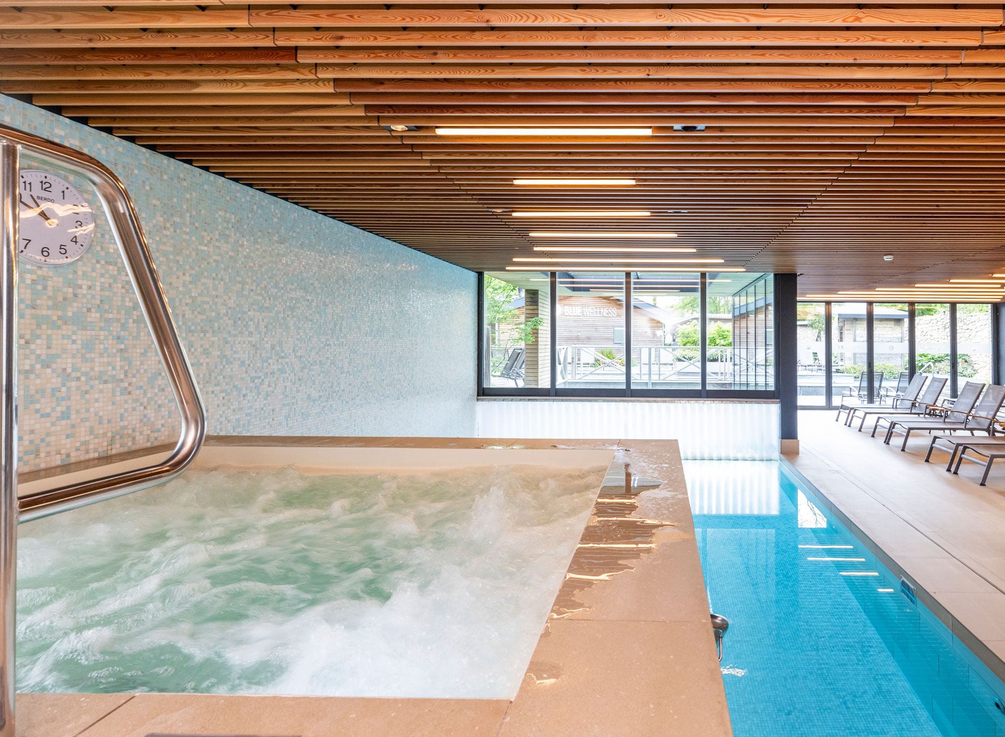Un espace bien-être comprenant un jacuzzi, une piscine et des chaises longues.