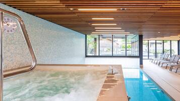Un espace bien-être comprenant un jacuzzi, une piscine et des chaises longues.