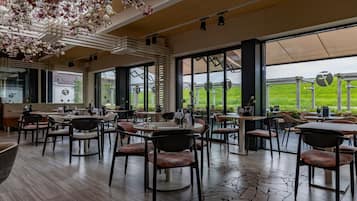 A restaurant with indoor seating, large windows, and a view of the outdoors.