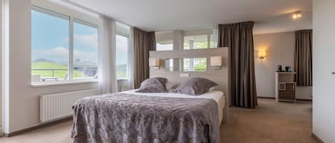 A bedroom with a bed, a window, a radiator, and a nightstand.