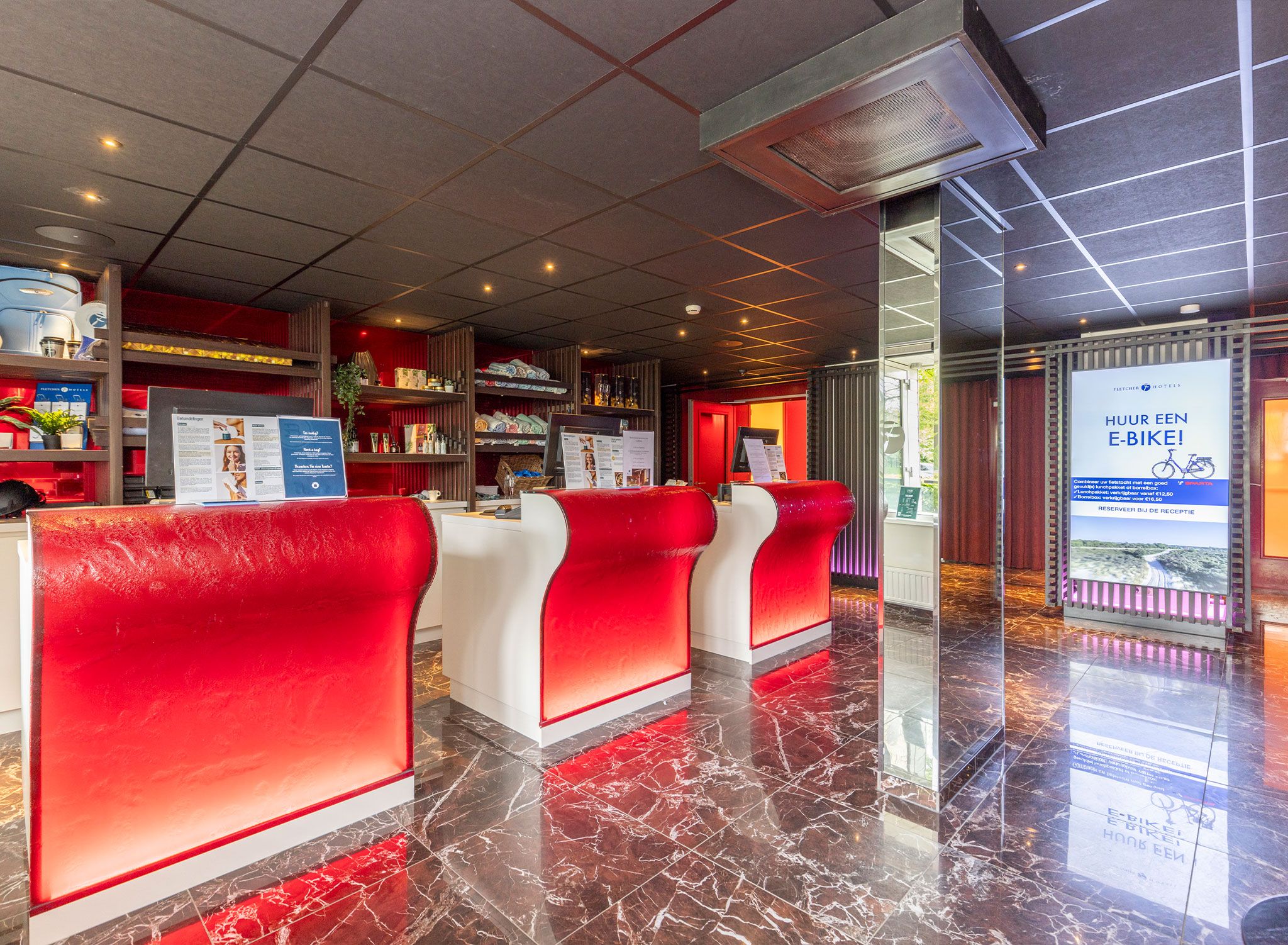 Een hotel receptie met een modern design, met een marmeren vloer en rode en witte zitplaatsen.