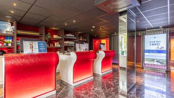 Een hotel receptie met een modern design, met een marmeren vloer en rode en witte zitplaatsen.