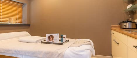 Una habitación limpia y moderna con una cama, una mesita de noche y un ventanal con persianas.