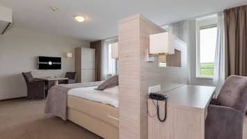 Ein Hotelzimmer mit Bett, Schreibtisch, Stuhl, Fernseher und Telefon.