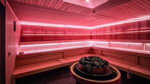 A sauna with wooden benches and a central heated stone feature.