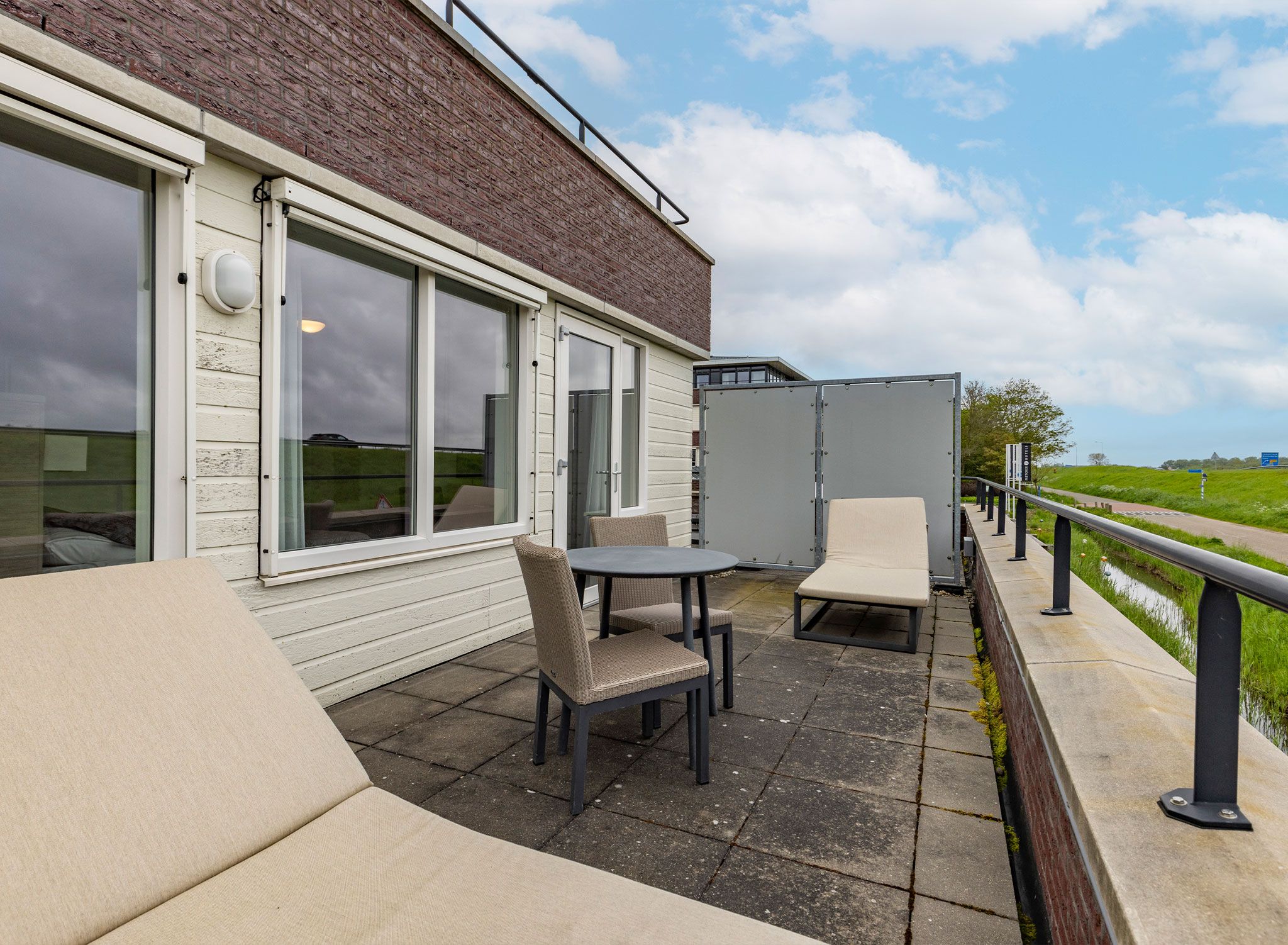 A patio with outdoor seating, a glass door entrance, and a view of the countryside.