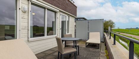 A patio with outdoor seating, a glass door entrance, and a view of the countryside.
