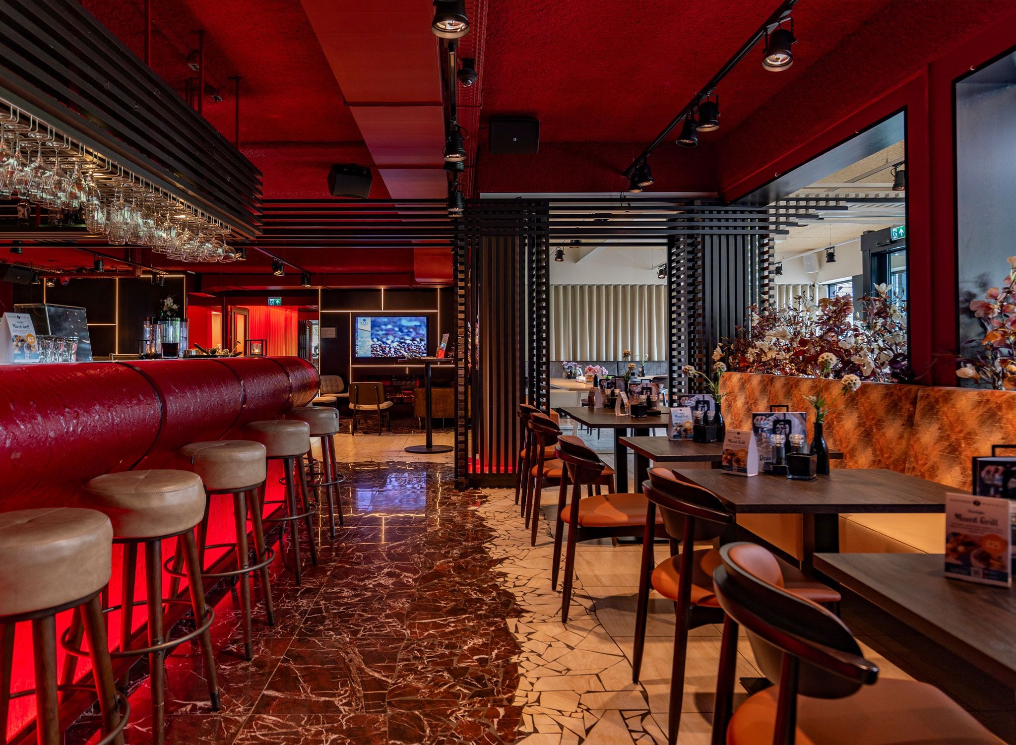 Een bar met krukken, een televisie en diverse zithoeken.