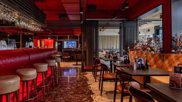 Een bar met krukken, een televisie en diverse zithoeken.