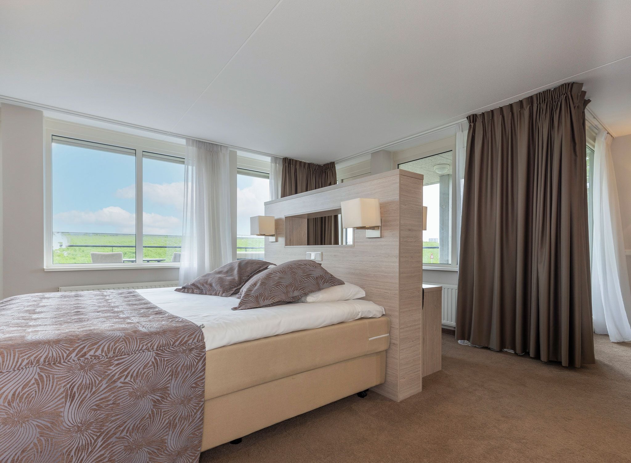 Un dormitorio moderno con una cama grande, un escritorio empotrado y vistas al exterior.