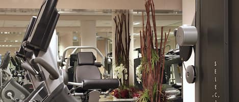 A gym with exercise equipment, a large mirror, and a potted plant.