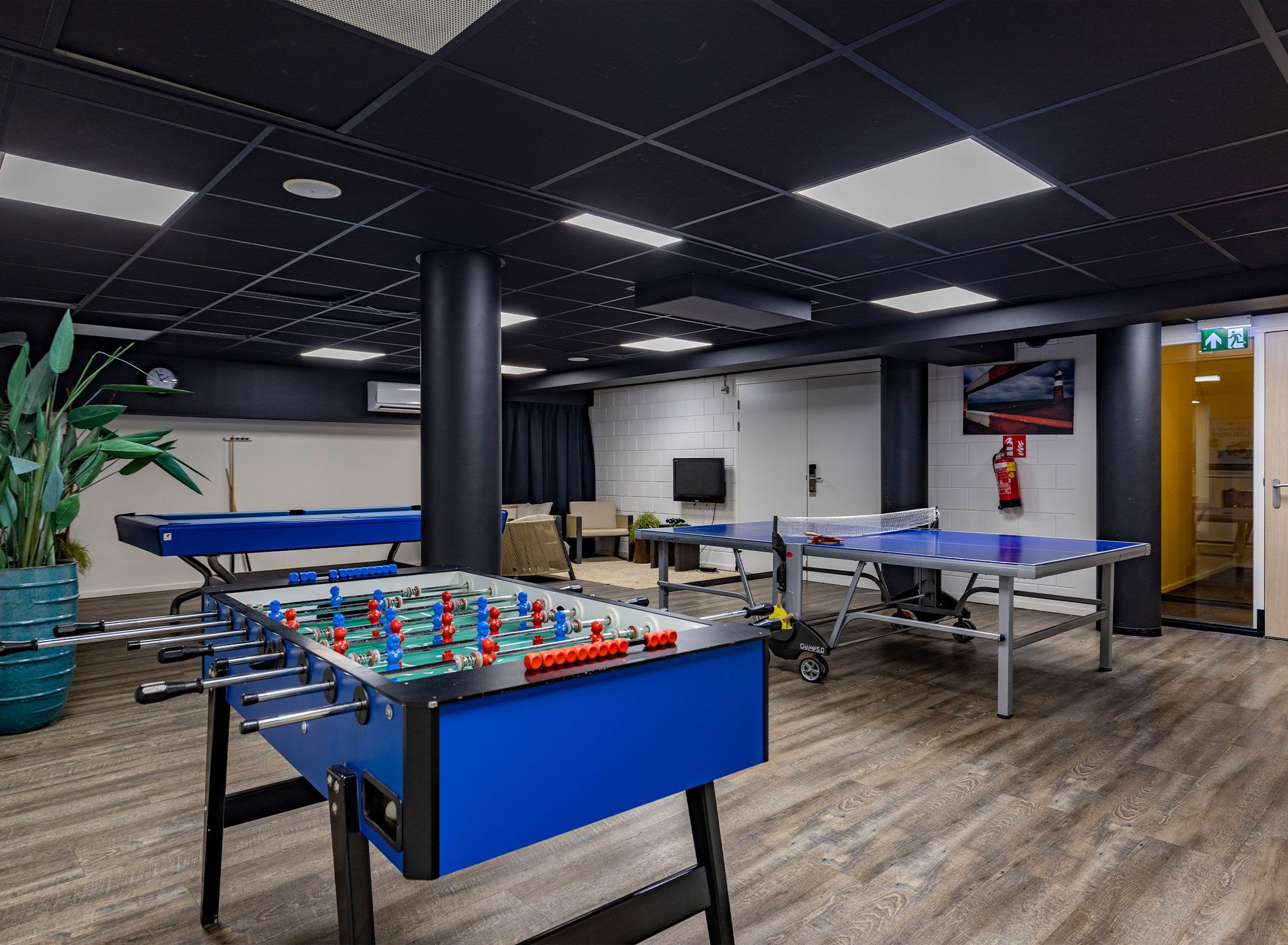 Ein Raum mit Tischfußball, Tischtennis und einem Fernseher.